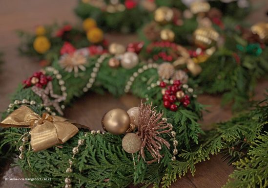 Weihnachtskranz mit goldenen Ornamenten, roten Beeren und dekorativen Schleifen.
