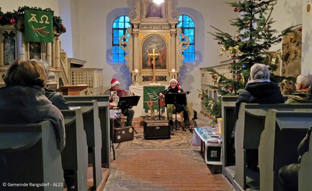 Musiker spielen in einer festlich geschmückten Kirche während einer Weihnachtsfeier.