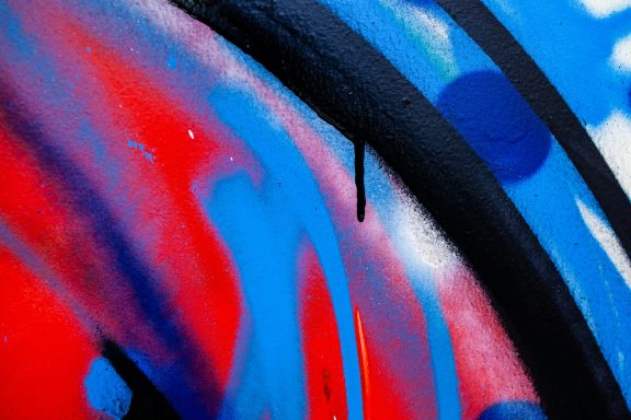 Bunte Graffiti-Muster in Rot, Blau und Schwarz mit geschwungenen Linien und Punkten.