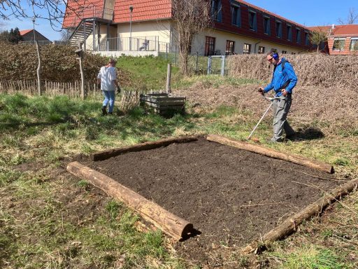 Gartenarbeit: Person bereitet einen Gemüsebeet-Rahmen auf einem sonnigen Grundstück vor.