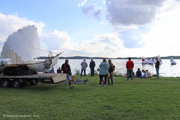 Menschen am Wasser, Kunstprojekte im Hintergrund.